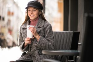 Ung kvinne som drikke kaffe på kafé