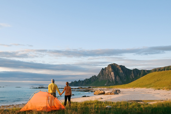 Par står med oppslått telt ved en strand i Lofoten.
